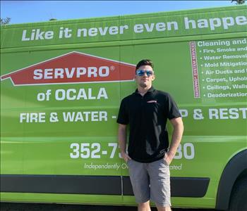 Cody standing in front of a green SERVPRO van