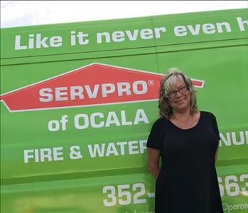 Lynette standing in front of a green SERVPRO van
