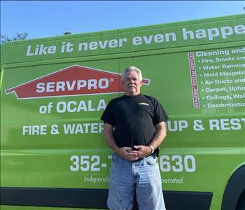 Richard standing in front of a green SERVPRO van