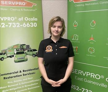 Hanna Wilson standing in front of 2 SERVPRO green banners