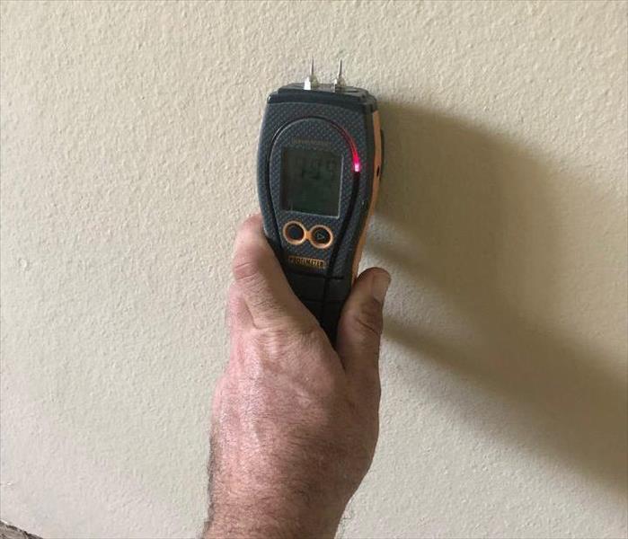 non penetrating Moisture Meter against wall showing the drywall is wet
