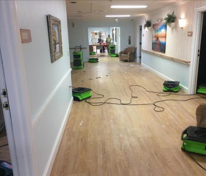 Drying Air Movers placed on the floor of this assisted living hallway