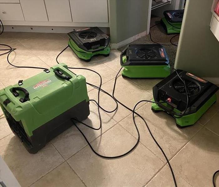 Professional air movers and dehumidifier in master bathroom drying walls, floors and cabinets