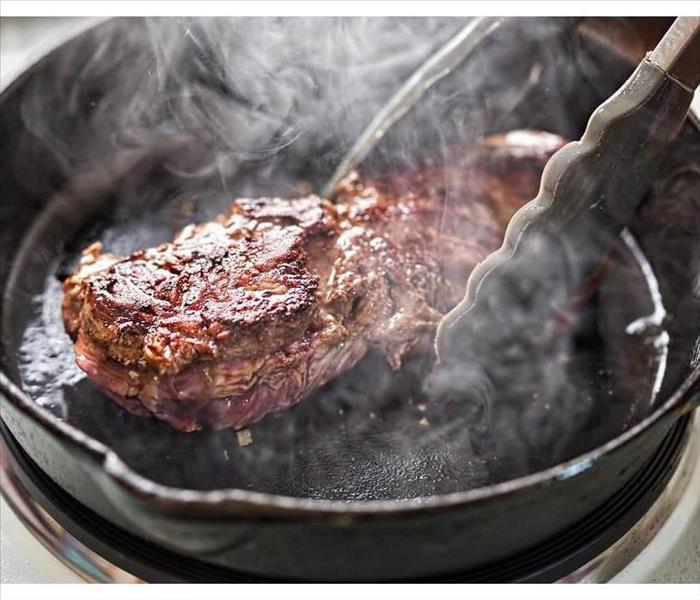 Photo of a steak burning in an iron skillet on the stove