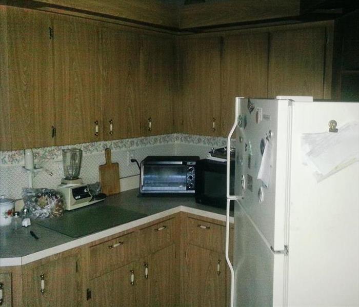 Kitchen cabinets and refrigerator that appear black because of smoke from a small electrical fire in the kitchen.