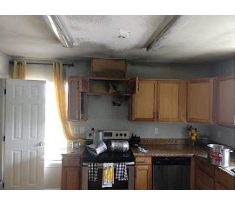 Picture of a kitchen that stove caught on fire damaging cabinets and wall.
